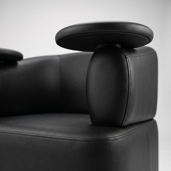 Female client seated in Globalstar MTS5 black leather manicure chair receiving nail treatment from technician in modern luxury salon