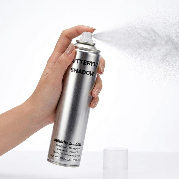 Hand holding a can of 'Butterfly Shadow' hair spray against a white background