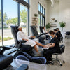 Woman receiving a pedicure in a modern salon with large windows.
